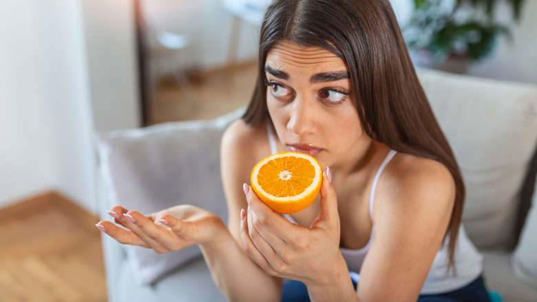 Young woman smelling orange