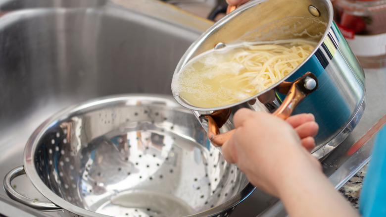 Separating water from spaghetti with colander