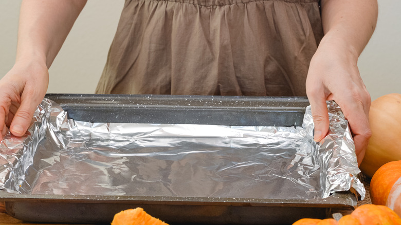 Person putting foil on baking sheet