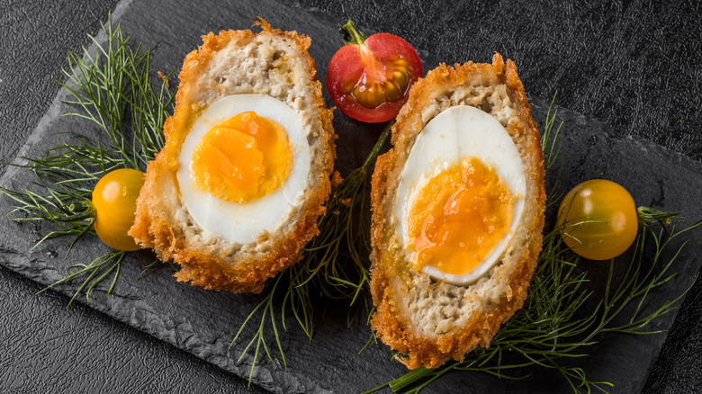 Scotch eggs with garnish on black slab