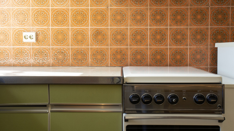 Orange tiles and green cabinets in retro kitchen