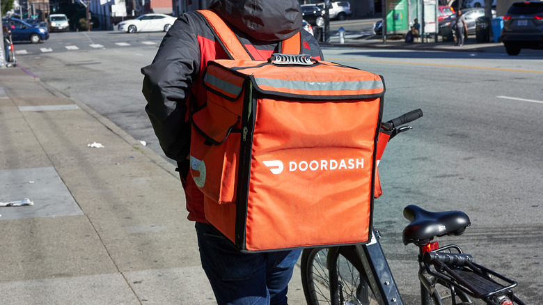 DoorDash rider with delivery bag and bicycle