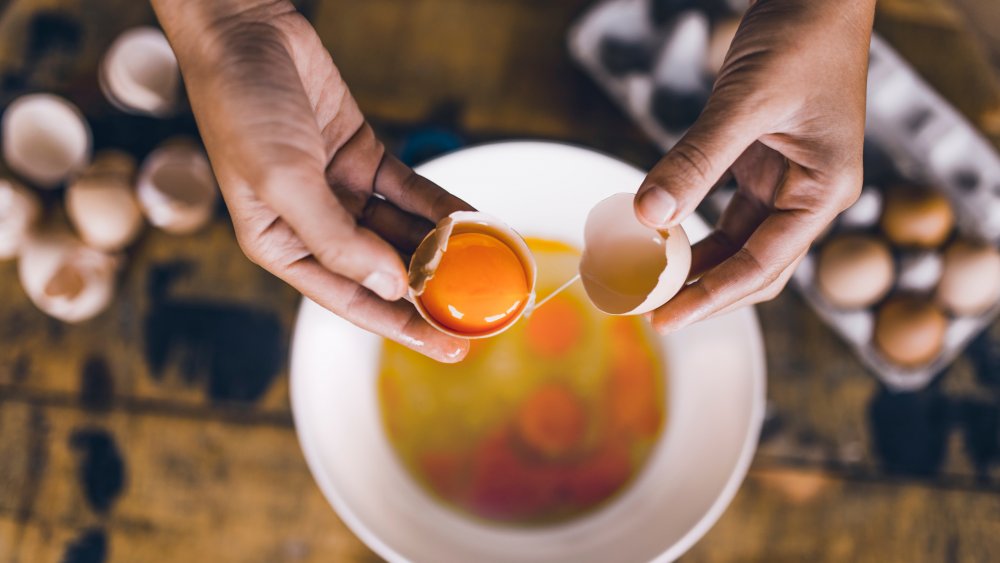 hands separating egg yolks from egg whites