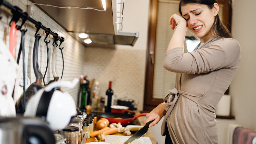 Woman cries while chopping onions