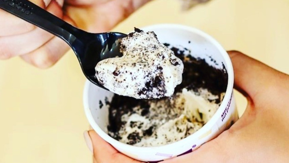 Hand spooning scoop of Oreo McFlurry from cup