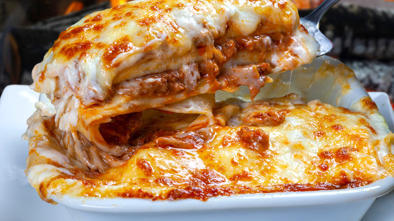 baking dish of cheesy lasagna with slice being cut