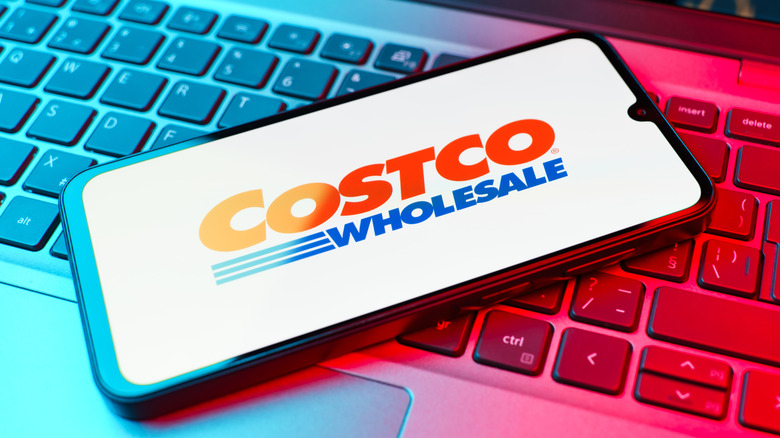 mobile phone displaying Costco logo on top of computer keyboard