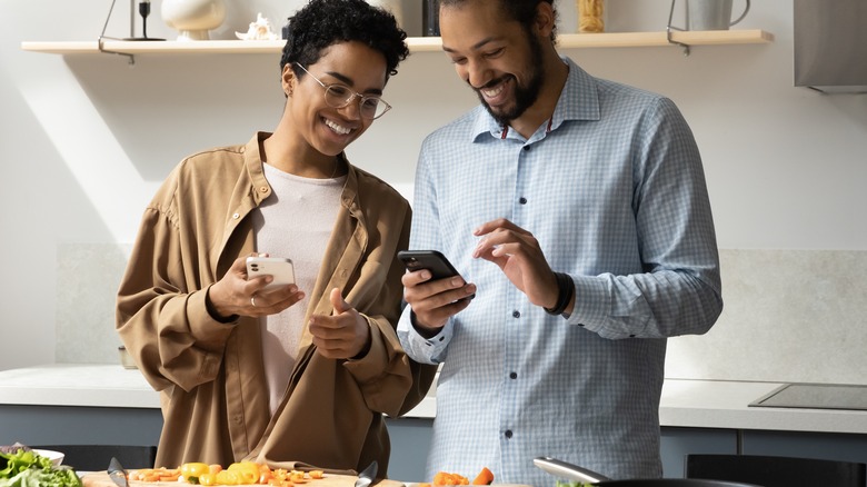 A couple smiling and laughing together in the kitchen