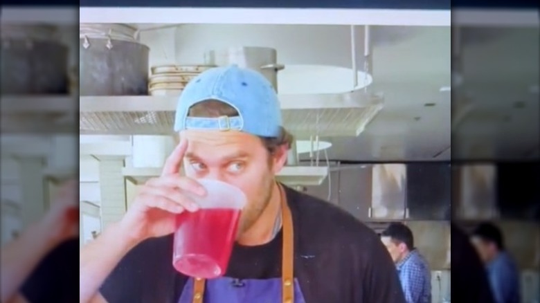 Person drinking red liquid of plastic container