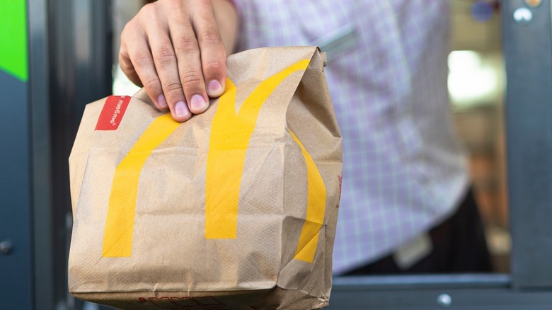 mcdonald's employee handing bag out drive thru window