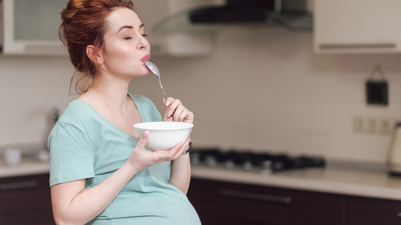 Pregnant person happily eating from bowl