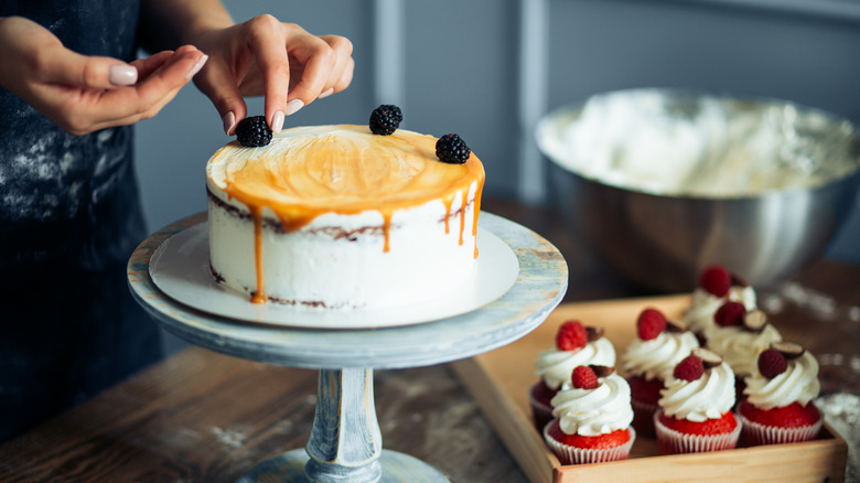 Hands decorating a round cake