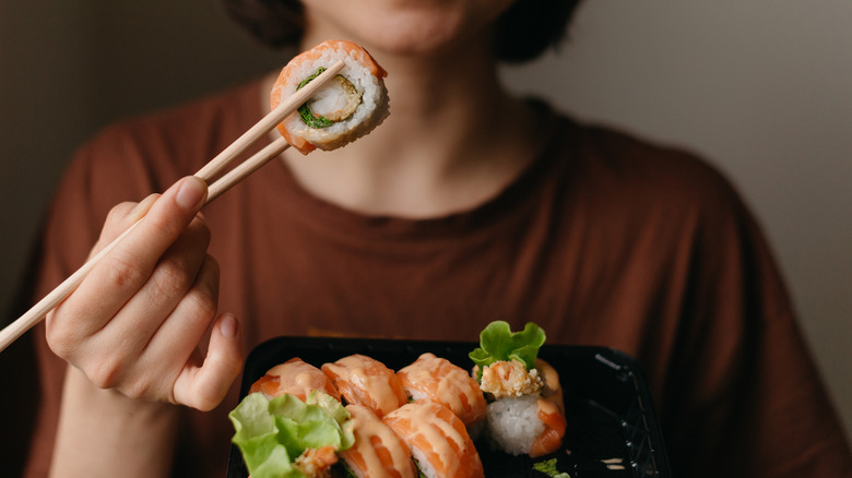 woman holding sushi with chopsticks