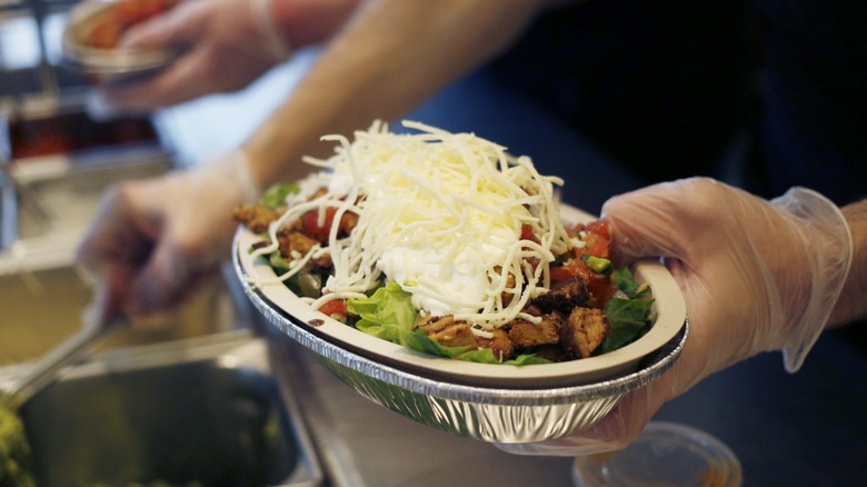 Chipotle worker assembling burrito bowl