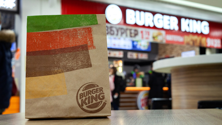 Burger king bag sitting on a table inside a Burger King restaurant 