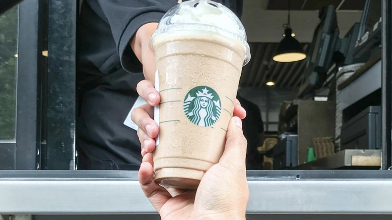 employee handing over Starbucks frappuccino