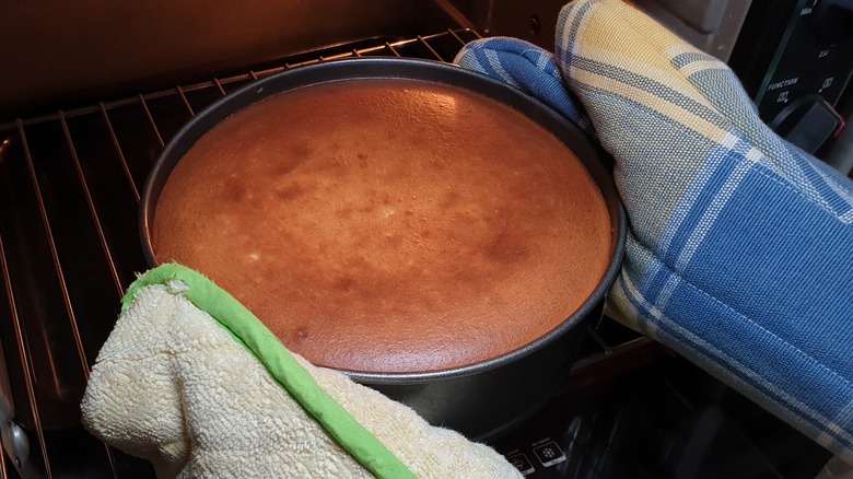 hands removing cake from oven