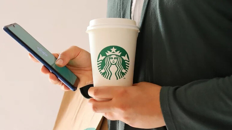 Person holding phone and Starbucks cup