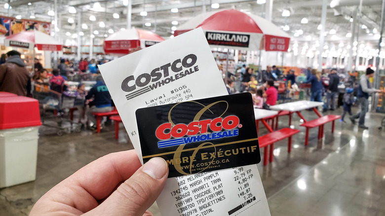 Person holding Costco membership card and receipt
