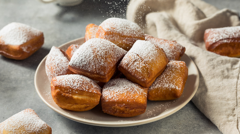 sprinkling beignets with powdered sugar