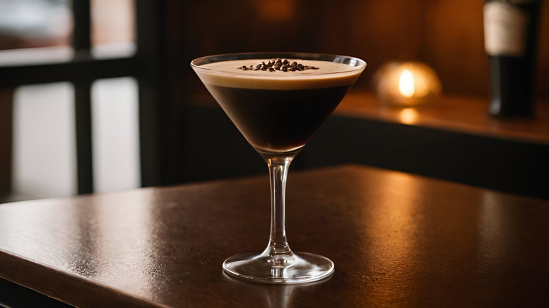 An espresso martini on dark wooden table in low bar lighting, surrounded by more dark wood.