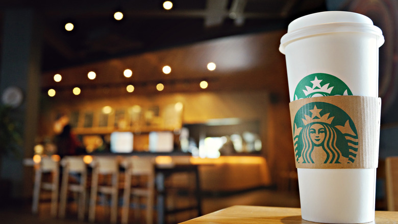 A Starbucks coffee cup sits on a table inside a store