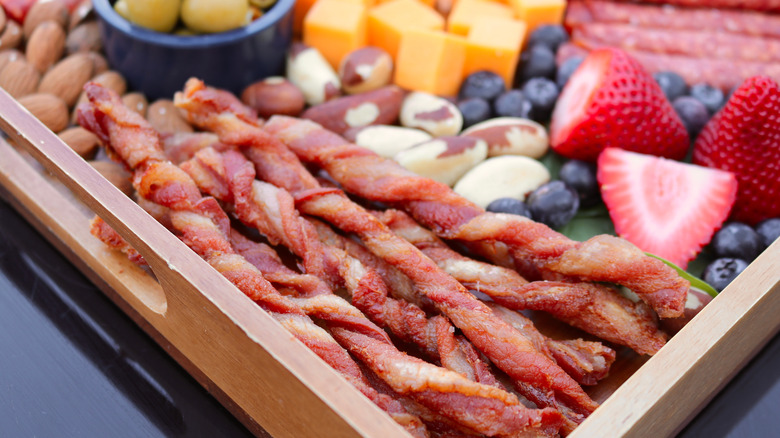 Twisted bacon on charcuterie cheese board