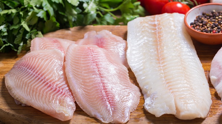 Cod and tilapia filets on wooden board