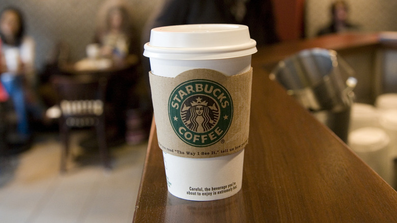 Starbucks cup on a ledge in the foreground of the cafe