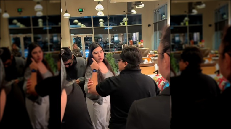 Starbucks employee points at an unknown person while a customer gently touches their arm