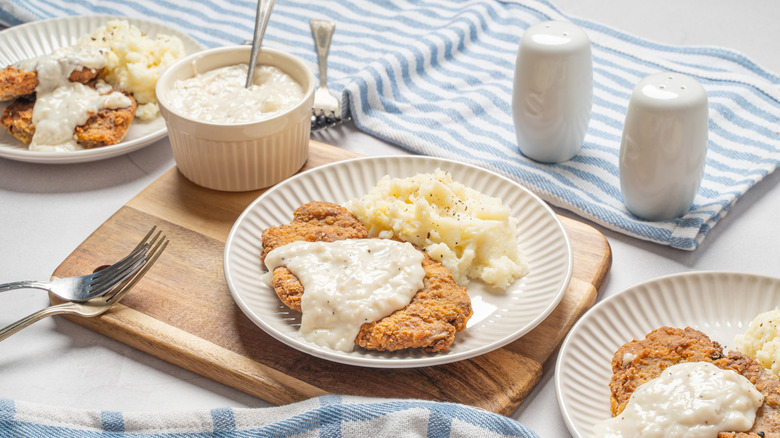 Homemade chicken-fried steak on white plates with mashed potatoes.