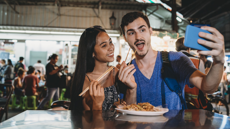 couple selfie eating street food