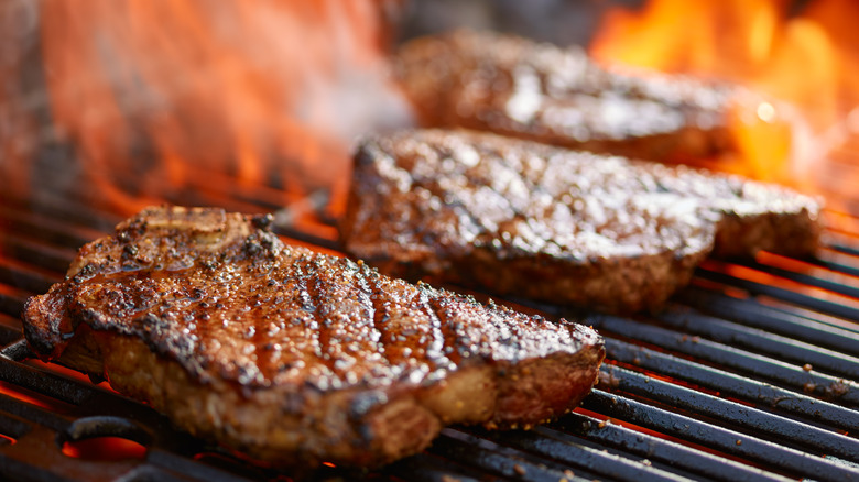 Multiple steaks cooking on grill 