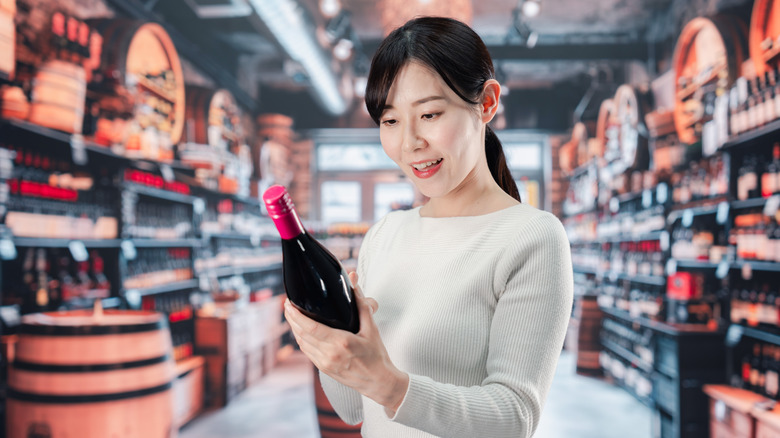 Woman looking at bottle of wine in store