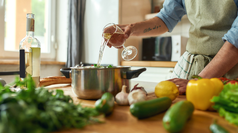 Glass of wine being poured into cooking pot