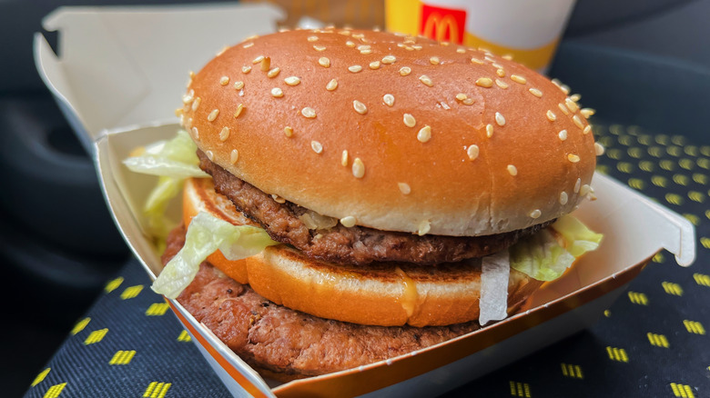 Closeup of McDonald's Big Mac burger with drink in the background.