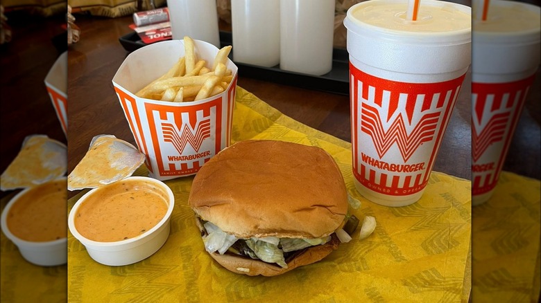 Meal from Whataburger with burger, fries, beverage, and opened sauce cup.