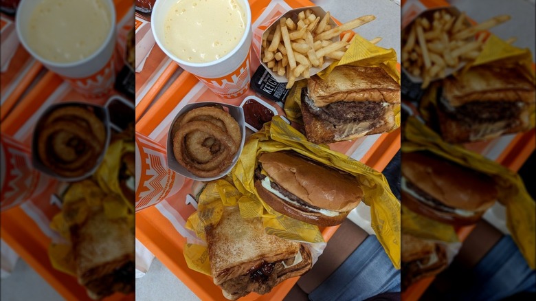 At Whataburger, sandwiches, fries, onion rings, and beverage are spread out on a try.