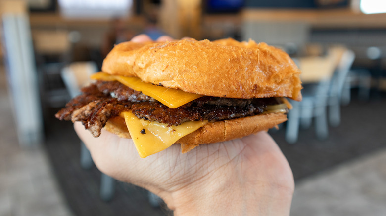 Hand holding ButterBurger inside Culver's restaurant.