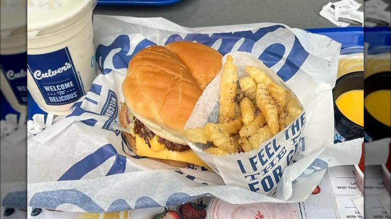 Culver's cheeseburger, french fries, and milkshake on tray in restaurant.