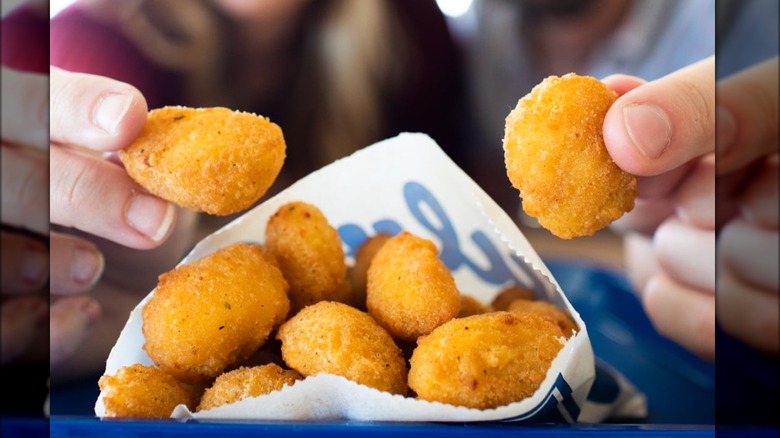People eating Culver's cheese curds from paper bag.