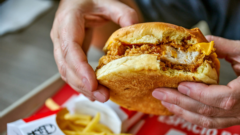 Person holding a chicken sandwich from KFC with both hands.