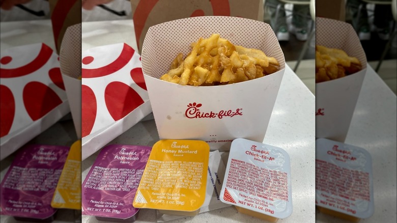 Chick-fil-A fries with assorted dipping sauces on table inside restaurant.