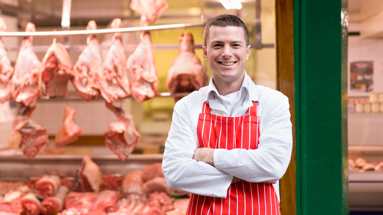 Smiling butcher in front of shop