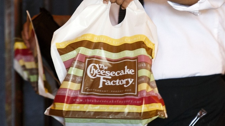 Someone holding a bag from Cheesecake Factory