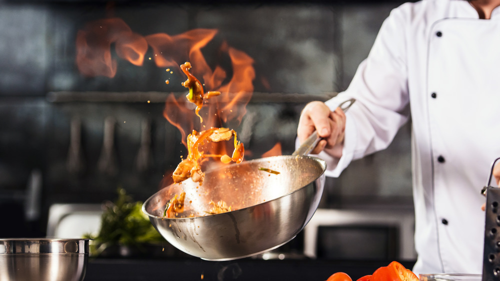Chef cucina con wok e fuoco