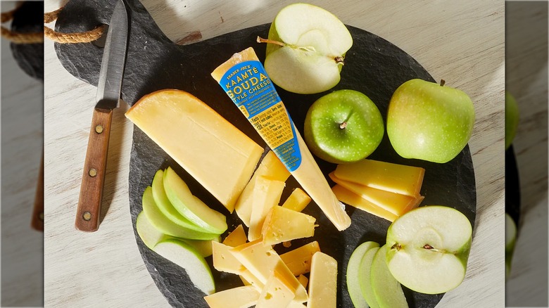 Cutting board with sliced green apples and gouda cheese