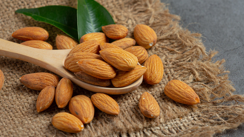 Almonds and wooden spoon on burlap cloth