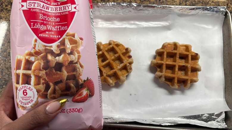 Hand holding Trader Joe's brioche-style liège waffles package with waffles atop tray on counter below