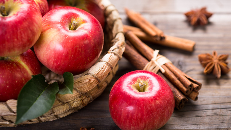 Red apples in a basket with cinnamon sticks on the side